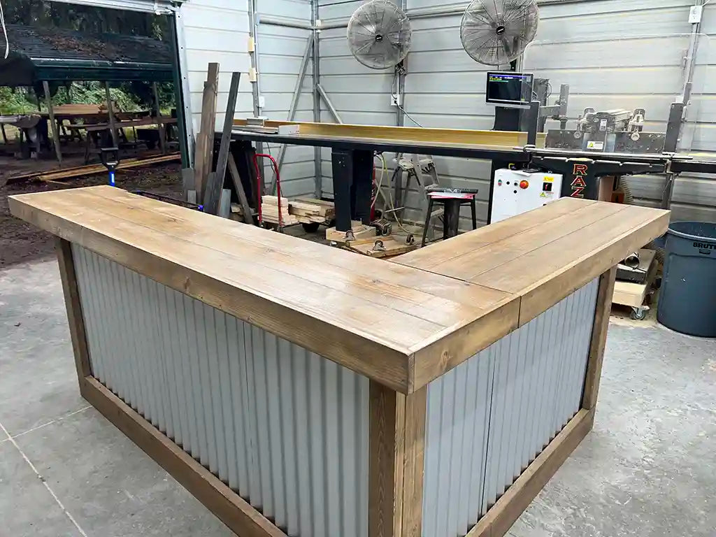 L-shaped wood and metal portable bar with corrugated metal front and mushroom wood finish.