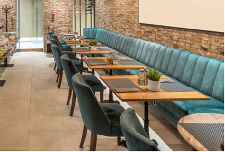 Wood restaurant table top shown in a dining room setting with upholstered half-booth seating against the wall and matching dining chairs around the table