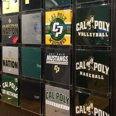 Group of acrylic T-shirt display boxes arranged vertically on a retail wall.