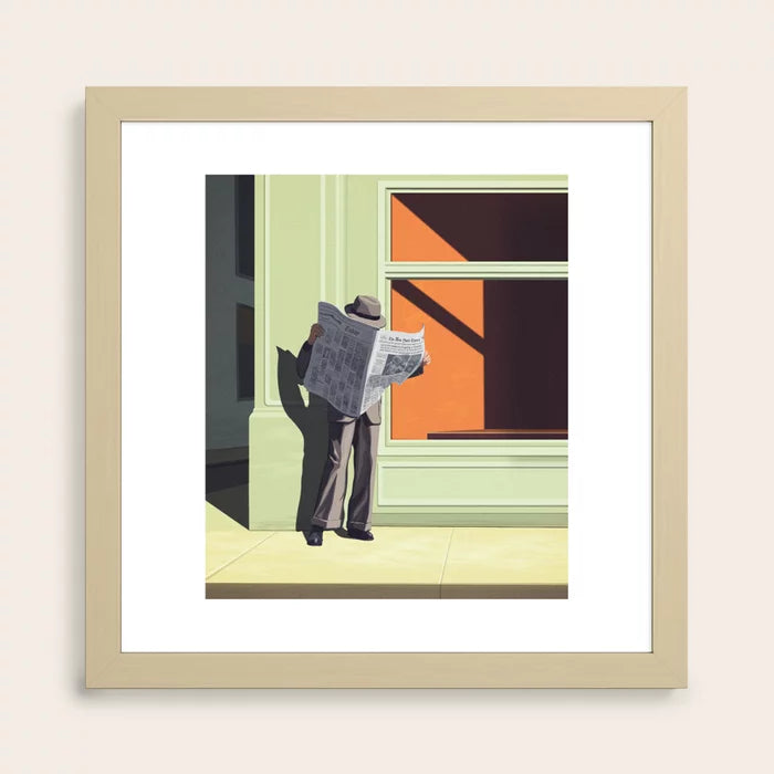 Anonymous Reader art print in maple frame shown in warm coffee shop interior
