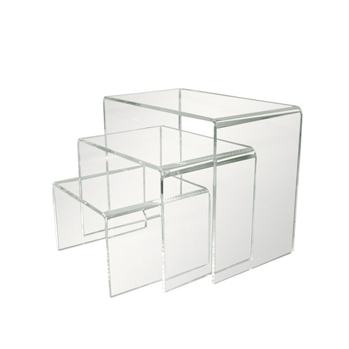 Set of three clear acrylic display risers in graduated sizes arranged together to create a multi-level retail presentation.