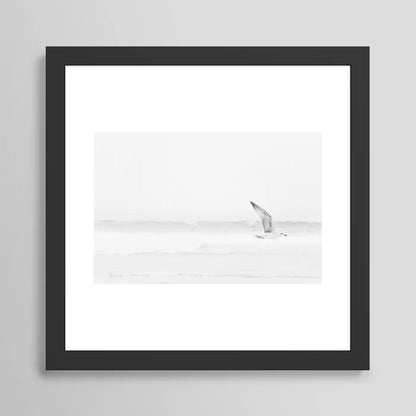Minimal black and white seagull ocean photography art print in black wood frame – modern coastal wall decor by Ingrid Beddoes